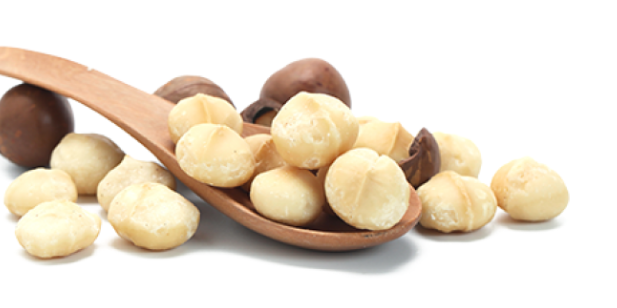 Whole macadamia kernels and shells with a wooden spoon